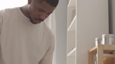 Haftasonu kahvaltısı için meyve kesen ev elbiseli genç siyahi adam yavaşlıyor.