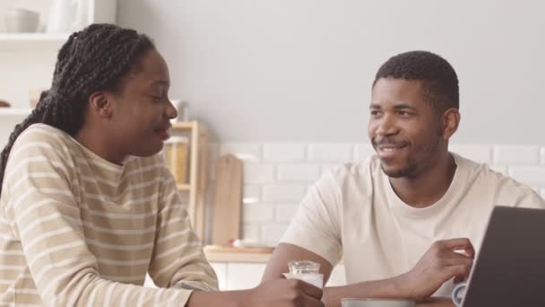 中等速度的年轻浪漫的非洲裔美国夫妇面带微笑地看着对方 在他们舒适公寓的简约厨房里一起吃早餐 — 图库视频影像