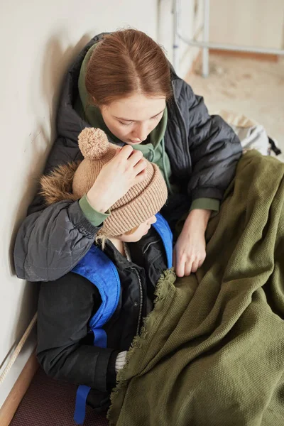 年轻母亲抱着儿子躲藏在难民庇护所并试图保暖的画像 — 图库照片