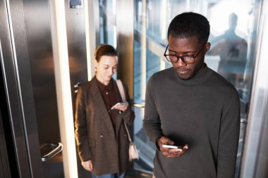 Modern ofis binasında cam asansörlü iki genç iş adamına yüksek açı, kopyalama alanı