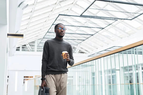 Graphic portrait of young black businessman walking in office building while starting work at morning, copy space