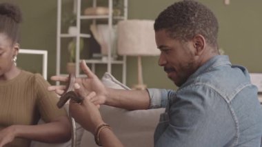 Oturma odasında kız arkadaşıyla birlikte dizüstü bilgisayar kullanarak kanepede otururken elinde kahverengi fare yılanı tutan siyahi adamın yavaşlığı.