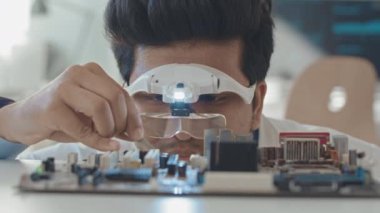 Laboratuvarda anakart tamir ederken özel lens hoparlörü gözlüklü erkek mühendisin cımbız kullanarak yavaş yavaş yaklaşması.