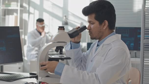 在显微镜下检查电脑芯片 与同事一起在实验室工作的男性工程师拖延时间 — 图库视频影像