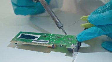 Laboratuvarda PCB lehimleyen mavi tek kullanımlık eldivenli tanımlanamayan elektronik mühendisinin yavaş yavaş yakın çekimi