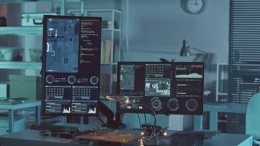 Elektronik mühendisinin iş yerinde, baskılı devre kartları ve karanlık laboratuardaki verileri olan iki bilgisayar monitörüyle yavaşlayan insanlar yok.