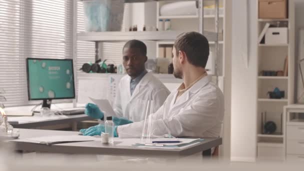 两位不同的男性科学家对培养皿中的液体物质进行生物技术研究 并对实验室的化学反应进行分析 其速度为中等 — 图库视频影像