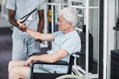 Tekerlekli sandalyedeki son sınıf öğrencisinin, klinikteki spor salonunda rehabilitasyon egzersizleri yaparken,