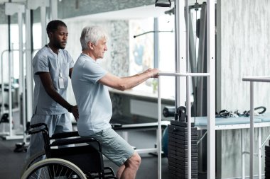 Tıbbi klinikte rehabilitasyon egzersizleri yapan son sınıf öğrencisinin portresi. Terapistin de yardımıyla.