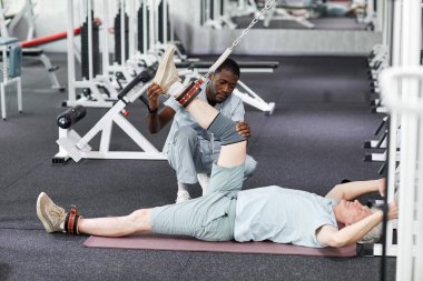 Afrikalı Amerikalı terapistin portresi rehabilitasyon kliniğinde kıdemli bir hastaya yardımcı oluyor.