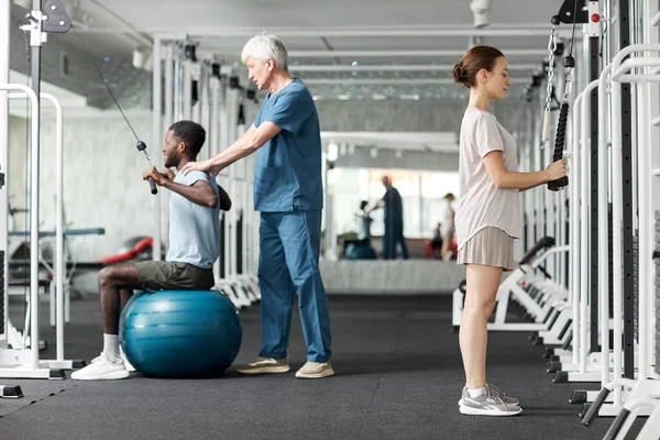 Fuld Længde Portræt Mennesker Der Bruger Fysioterapi Maskiner Gym Rehabilitering - Stock-foto