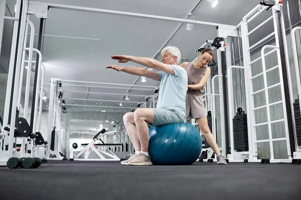 stock image Portrait of young female therapist assisting senior man doing physical exercises in rehabilitation clinic, copy space