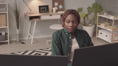 İki bilgisayar ekranının önünde oturan, merkez ofisten çalışan Afrikalı Amerikalı genç kadının belini kaldır.