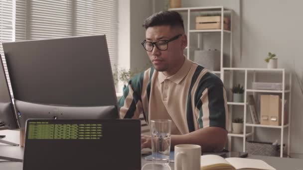 オフィスでコンピュータ上の眼鏡入力プログラムコードの若いアジアのソフトウェア開発者の中低速 — ストック動画
