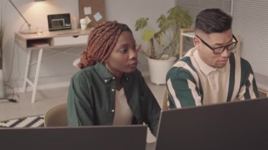 Bilgisayar monitörleri başında oturmuş, yazılımları tartışan, modern bilişim şirketinde birlikte çalışan iki genç programcının belini bük.