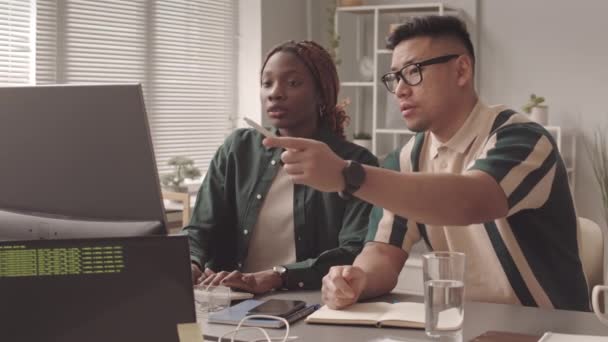 現代のオフィスで一緒に作業しながら ソフトウェア開発を議論するプログラマーの多民族のカップルの中低速 — ストック動画