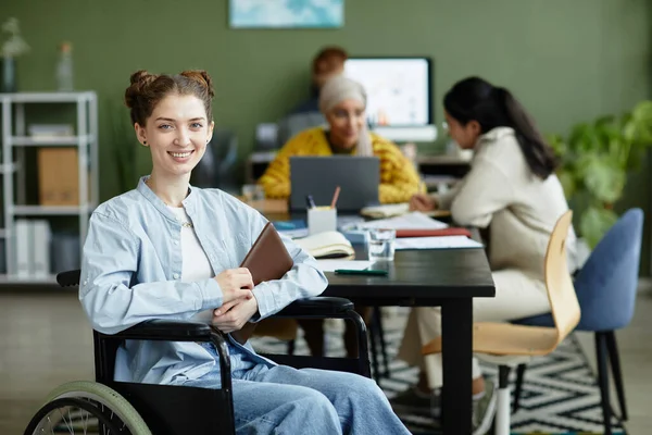 Portret Uśmiechniętej Młodej Kobiety Wózku Inwalidzkim Patrzącej Kamerę Podczas Pracy — Zdjęcie stockowe