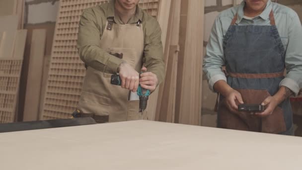 Junger Schreiner Bohrt Mit Lochsäge Stück Holz Holzwerkstatt Mit Kollegin — Stockvideo