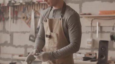 Genç erkek marangoz, atölyede mobilya yaparken, odun parçasıyla çalışırken cila diski kullanıyor.