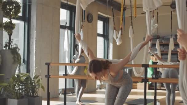 集体练习赛期间 在丝绸吊床上倒立的女子空中瑜伽训练员向学生展示运动的慢动作 — 图库视频影像