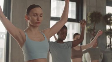 Koçu parlak geniş stüdyoda yoga yapan bir grup gevşemiş genç kadın.