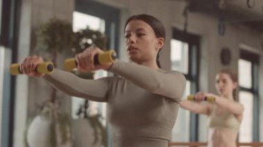 Stüdyoda grup çalışması sırasında dambıl gibi öne doğru yükselen güzel bir kadının yavaşlaması.