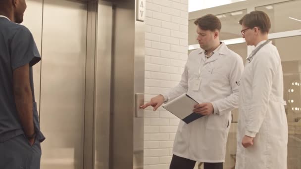 Medium Slowmo Van Diverse Medische Team Praten Afwachting Van Lift — Stockvideo