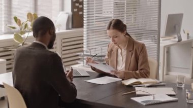 Genç Afrikalı Amerikalı bir adamın iş görüşmesinde kadın İK yöneticisine özgeçmişini ya da kapak mektubunu verirken orta derecede yavaşlaması.