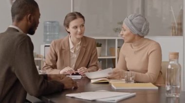 İki kadın İK yöneticisiyle ofisinde iş görüşmesi yapan ve CV 'sine bakıp ona sorular soran Afrikalı Amerikalı bir adamın orta boy yavaşlığı.