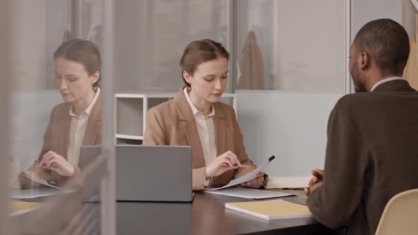 女性時間管理者インタビュー若いです黒男 オフィスのデスクで互いに前に座って — ストック動画