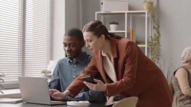 Ofisteki ilk gününde yeni bir çalışana laptopta çalışma programını gösteren beyaz bir kadın.