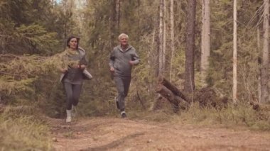 Aktif, olgun bir çiftin sabah ormanda birlikte koşması.