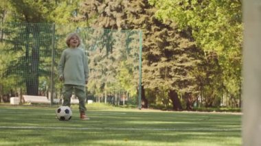 Babasıyla birlikte güneşli bir günde parkta yeşil alanda futbol oynayan Kafkas 'lı 7 yaşındaki bir çocuk.