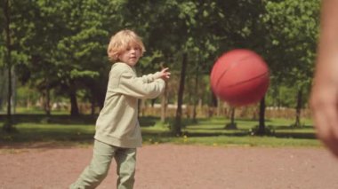 Güneşli bir günde babasıyla parkta oynarken basketbol oynayan 7 yaşındaki tatlı sarışının yavaşı.