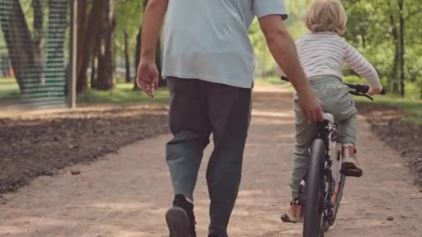 Vista Trasera Lenta Del Hombre Enseñando Pequeño Hijo Montar Bicicleta — Vídeos de Stock