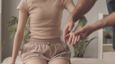 Kadın hastaların kollarına ve ellerine Kinesio bantları yapıştırarak dirsek eklemlerindeki ağrıyı azaltmaya yardımcı olan yavaş fizyoterapist.