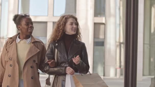 2人の魅力的な若い多民族の女性の中低速ウィンドウディスプレイを見て 屋外で一緒に買い物をしながら議論を持つ — ストック動画