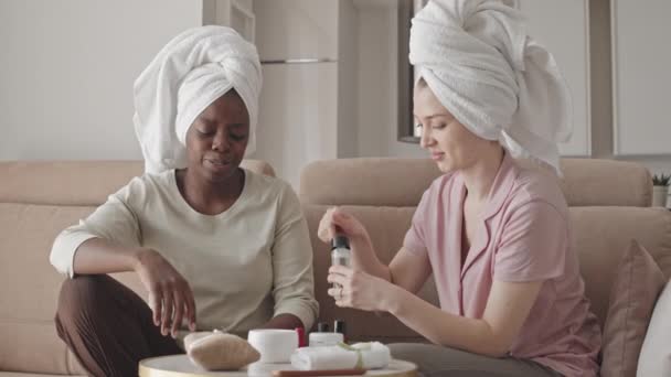 两个年轻的多民族女孩 头上戴着白色毛巾 在家里一起做日常护肤工作时 用面部石英滚筒 她们的动作有点慢 — 图库视频影像