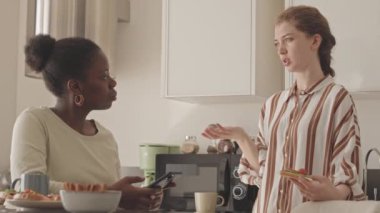 Mutfakta ev yapımı sandviçler yerken konuşan iki kadın arkadaşın orta derecede yavaşlaması.