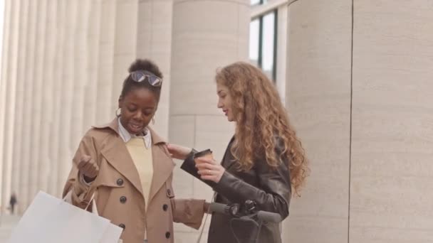 市内中心部で買い物をした後に屋外で友人に会う若いアフリカ系アメリカ人女性の中低速 抱擁で挨拶や会話を開始 — ストック動画