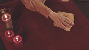 Tanınmayan falcı tarafından yukarıdan kırmızı kadife kumaşın üzerine tarot kartları dağıtılıyor.