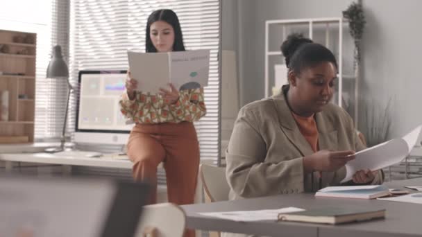 两名多族裔女性同事在一起查阅商业文件 在办公室一起工作 进展缓慢 — 图库视频影像