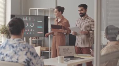 Modern ofisteki meslektaşlarına ürün sunumu yapan pazarlama uzmanlarından oluşan orta yavaş bir grup.