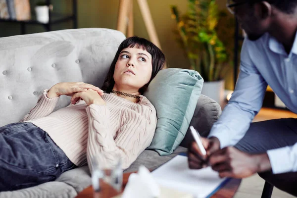 年轻女子躺在沙发上接受心理治疗 坦白交代问题 仰视心理医生 — 图库照片