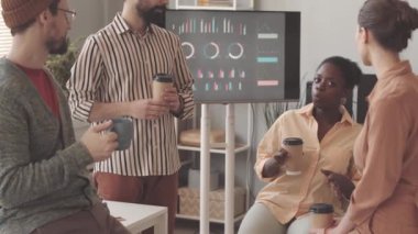 İş yerinde kahve molası sırasında sohbet eden çok ırklı, yaratıcı genç bir grup.