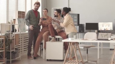 İş yerinde akıllı telefondan komik selfie portreleri çeken çok ırklı iş arkadaşlarının yavaşlaması.