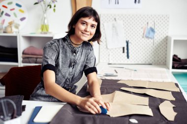 Gülümseyen genç terzi elbise detaylarını özetliyor ve kesiyor