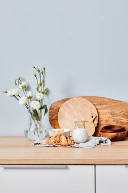 Taze kruvasan ve mutfak masasının üstünde süt taneleri ve arka planda vazoda beyaz çiçekler.