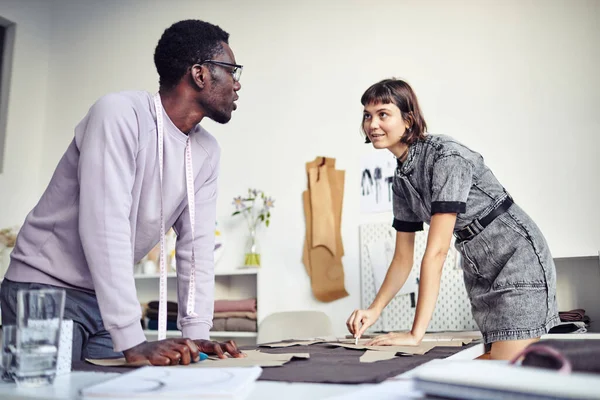 stock image Fashion design students learning tailoring in classroom, they are outlining cardboard sewing pattern on fabric