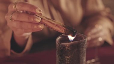Falcının palo santo çubuğunu yakmak için mum kullanıp kameraya üflediği yavaş çekim.
